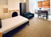 Thumbnail 2 of 12 - a bedroom with a bed and a living room with a fireplace