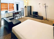 Thumbnail 4 of 12 - a bedroom with a bed and a living room with a kitchen