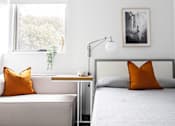 Thumbnail 7 of 11 - a bedroom with a bed with orange pillows and a window