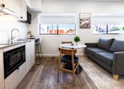 Thumbnail 5 of 20 - a living room with a kitchen and a couch and a table