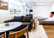 Thumbnail 2 of 20 - a living room with a couch and a table and a bed