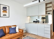 Thumbnail 9 of 11 - a living room with a couch and a kitchen in the background