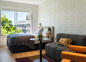 Thumbnail 4 of 9 - a bedroom with a bed and a couch and a table