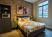 Thumbnail 10 of 18 - a bedroom with a bed and a exposed brick wall