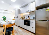 Thumbnail 17 of 20 - a kitchen with white cabinets and a table and a refrigerator