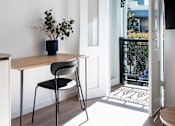 Thumbnail 11 of 14 - a small table with a black chair in a room with white walls and a staircase