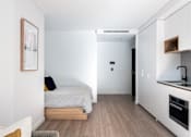 Thumbnail 10 of 14 - a small bedroom with a bed and a kitchen