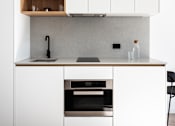Thumbnail 14 of 14 - a white kitchen with white cabinets and a black counter top