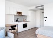 Thumbnail 13 of 14 - a bedroom with a bed and a kitchen with white cabinets