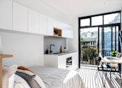 Thumbnail 9 of 14 - a bedroom with a bed and a kitchen with a large window