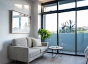 Thumbnail 7 of 14 - a living room with a couch and a table in front of a window