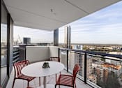 Thumbnail 10 of 13 - A balcony with a table and chairs overlooking a cityscape.