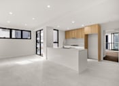 Thumbnail 7 of 13 - A modern kitchen with a white countertop and wooden accents.