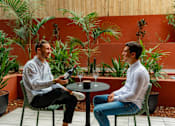 Thumbnail 3 of 21 - two men sitting at a table in a patio