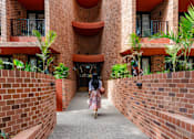Thumbnail 8 of 21 - a woman walking down a corridor in front of a building