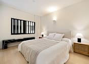 Thumbnail 19 of 24 - A bedroom with a large bed and a wooden nightstand.