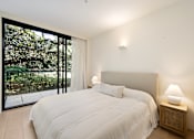 Thumbnail 14 of 24 - A bedroom with a large bed and a lamp on a side table.