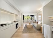 Thumbnail 20 of 24 - A modern kitchen with white cabinets and a large island.