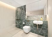 Thumbnail 15 of 24 - A modern bathroom with a toilet, sink, and marble countertops.