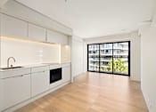 Thumbnail 23 of 24 - A modern kitchen with white cabinets and a wooden floor.