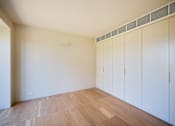 Thumbnail 17 of 24 - A room with white walls and wooden flooring with a row of white cupboards.
