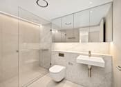 Thumbnail 21 of 24 - A modern bathroom with a toilet, sink, and glass shower.