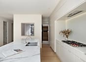 Thumbnail 24 of 24 - A modern kitchen with a marble countertop and a staircase in the background.