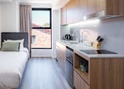 Thumbnail 6 of 11 - a small room with a bed and a kitchen