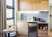 Thumbnail 3 of 11 - a small kitchen with a small table and a refrigerator and a sink