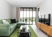 Thumbnail 6 of 19 - a living room with a green couch and a television