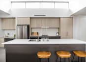 Thumbnail 15 of 19 - a kitchen with a white counter top and three wooden stools