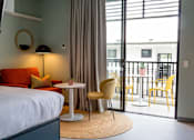 Thumbnail 6 of 11 - a hotel room with a bed and a balcony and a table and chairs