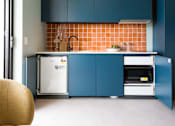 Thumbnail 2 of 11 - a small kitchen with blue cabinets and a white refrigerator