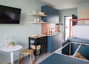 Thumbnail 1 of 11 - a small kitchen with a bed and a table in a small room