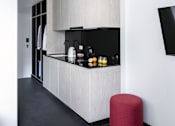 Thumbnail 8 of 12 - a white kitchen with a black counter and a red stool