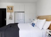 Thumbnail 12 of 13 - a bedroom with a bed and a refrigerator