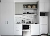 Thumbnail 5 of 13 - a black and white kitchen with white cabinets and a microwave
