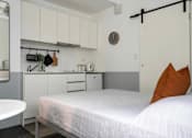 Thumbnail 2 of 11 - a small bedroom with a bed and a kitchen