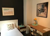 Thumbnail 5 of 5 - a small bedroom with a bed and a desk with a desk chair and a painting