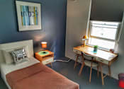 Thumbnail 2 of 5 - a bedroom with a bed and a desk and a window