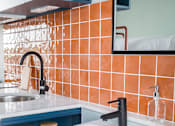 Thumbnail 10 of 11 - a white sink in a bathroom with orange tiles