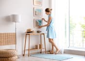 Thumbnail 9 of 25 - a woman in a blue dress puts a hat on a table