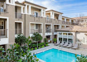 Thumbnail 5 of 21 - A large apartment complex with a pool in the foreground.