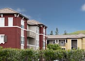 Thumbnail 4 of 21 - Apartment buildings with green shrubbery in front.