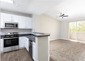Thumbnail 7 of 21 - A kitchen with white cabinets and a black countertop.
