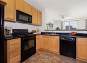 Thumbnail 19 of 21 - A kitchen with wooden cabinets and black appliances.