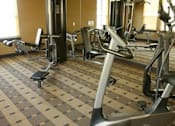 Thumbnail 25 of 48 - A gym with a variety of exercise equipment including treadmills, stationary bikes, and weight machines.