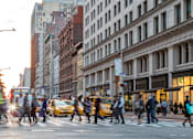 Thumbnail 13 of 32 - A busy city street with pedestrians crossing the road.