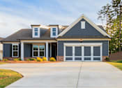 Thumbnail 14 of 32 - A house with a grey garage door and a brown roof.