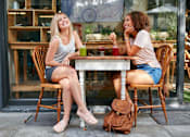 Thumbnail 2 of 10 - Two women sitting at a table outside a cafe.